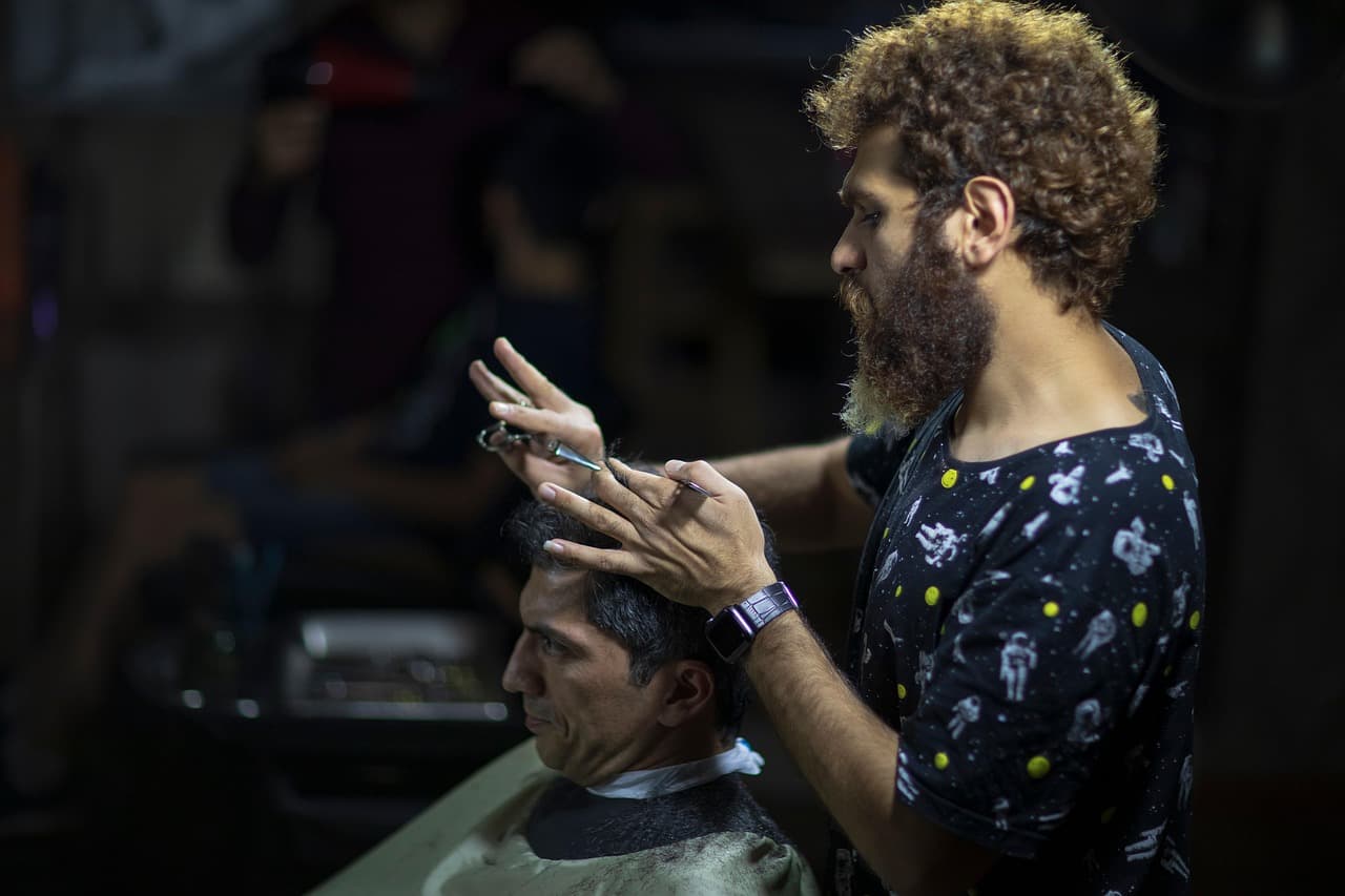 A barber with scissors and comb cutting a client's hair